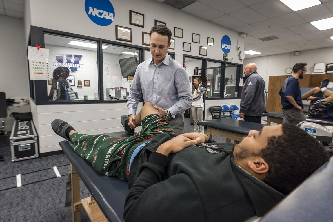 training room, athlete on table, trainer standing